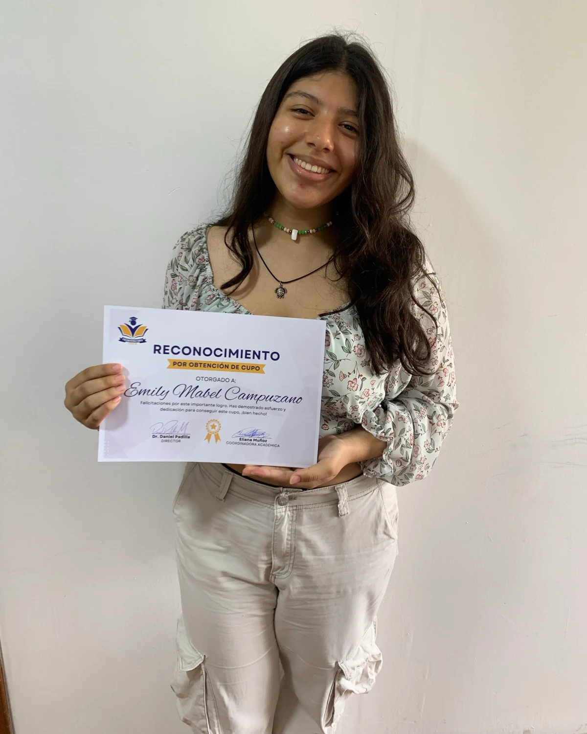 Emily Mabel Campuzano, estudiante de Preuniversitario Líder, sosteniendo su reconocimiento por obtención de cupo